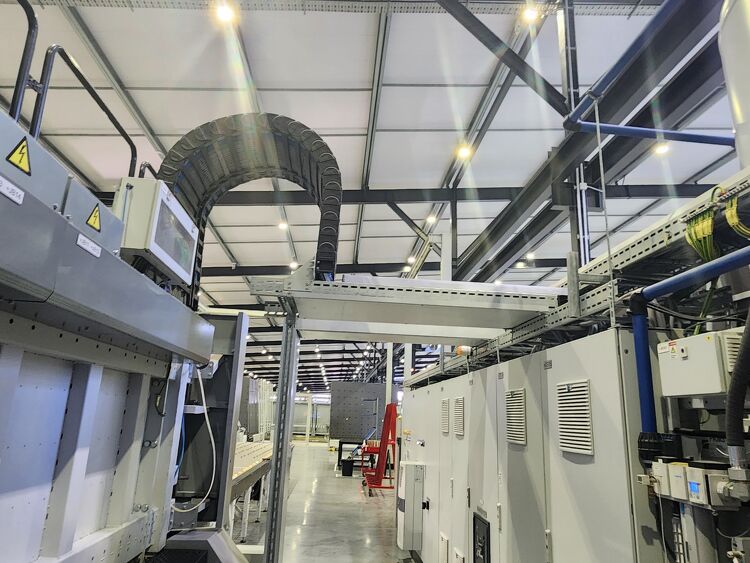 Detailed view of industrial equipment and overhead cable trays installed inside a modern warehouse.