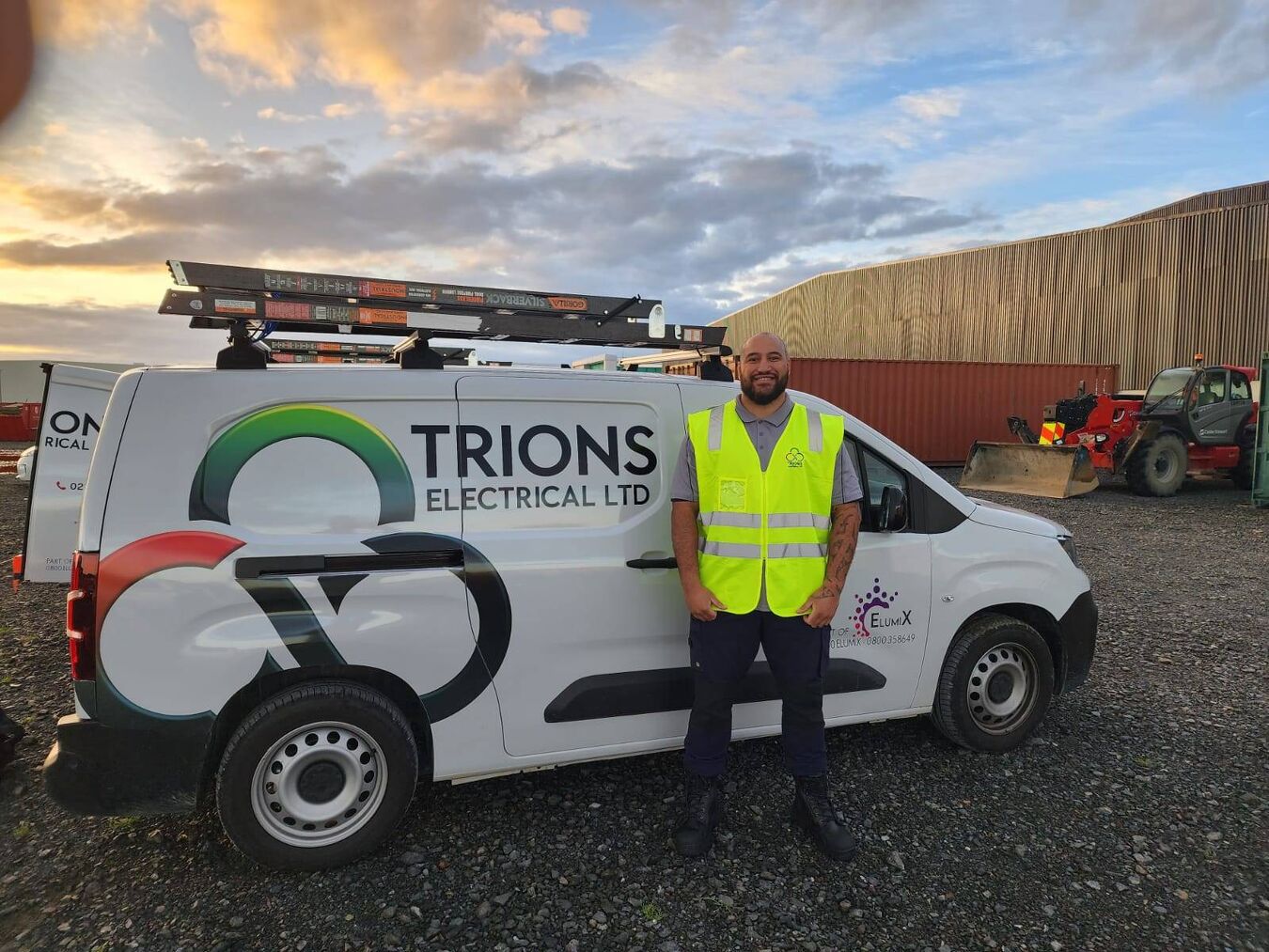 Trions Electrical technician standing in front of company van with branded signage.